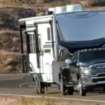A black RAM 3500 towing a large trailer on the road