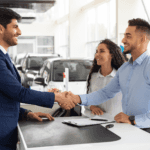 Two people shaking hands at a car dealership