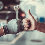 A service technician holding up a wrench and another person giving a thumbs up