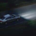 An overhead view of a silver Honda Accord driving at night with its headlights on