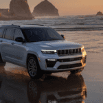 A silver Jeep Grand Cherokee driving along a beach