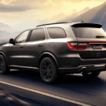 A gray Dodge Durango driving on the road by a hilly desert area