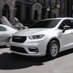 A silver Chrysler Pacifica driving down the road in a city