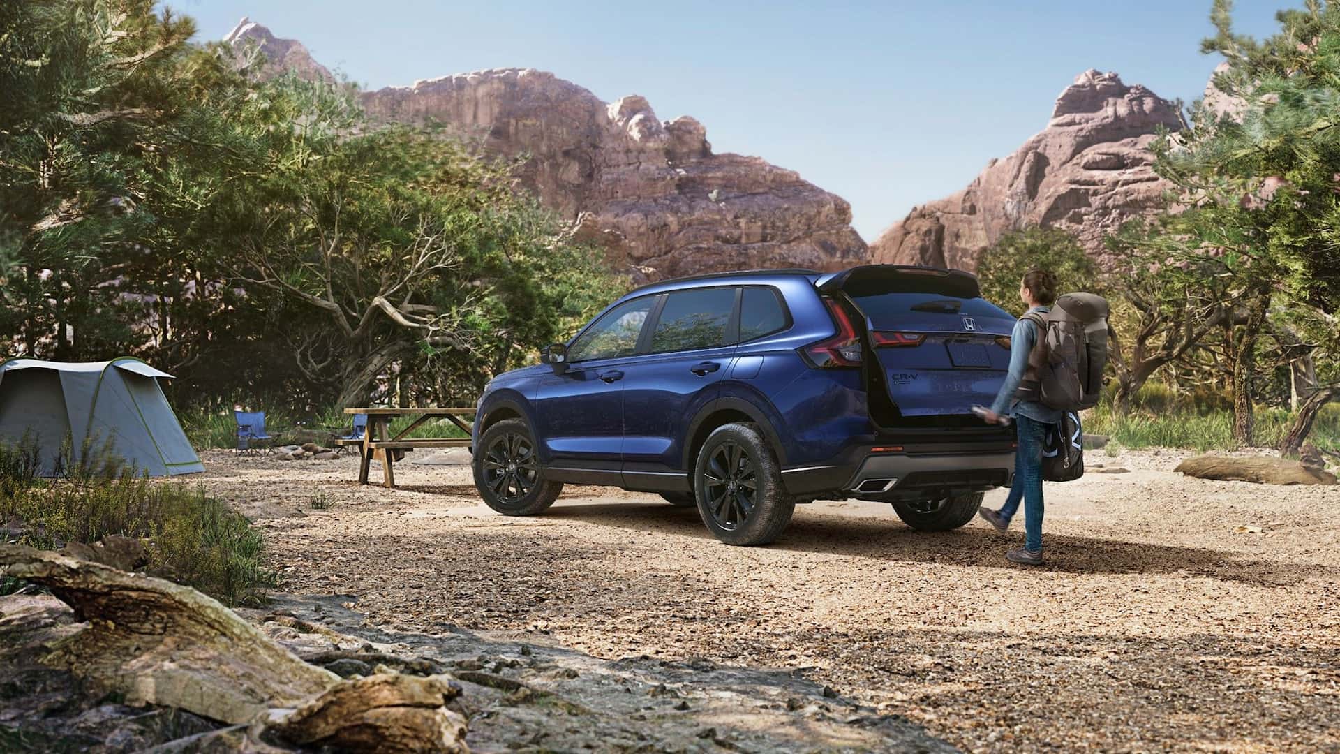 A blue Honda CR-V parked at a campsite with a person opening the trunk with the automatic tailgate