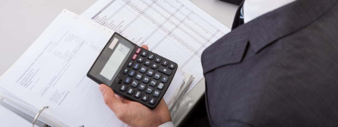 Honda financing professional using a calculator with a binder and papers in front of him