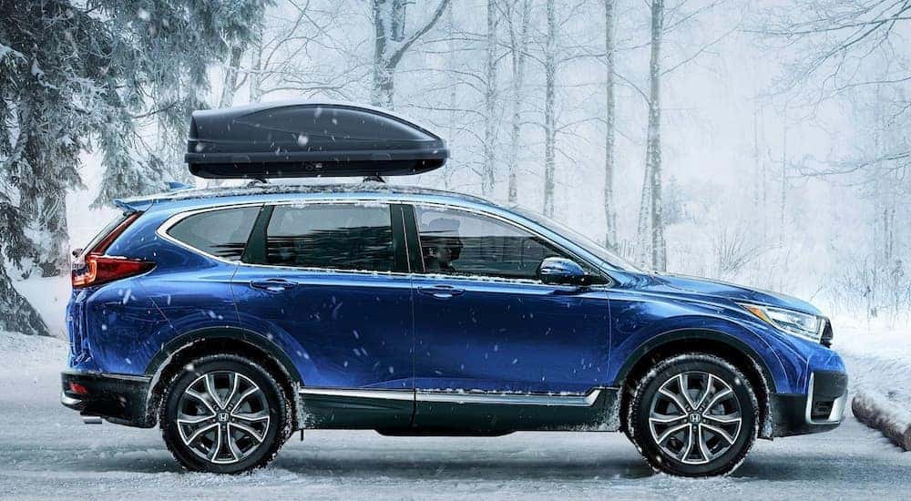 A blue 2022 Honda CR-V Touring is shown from the side parked on a snowy lot.