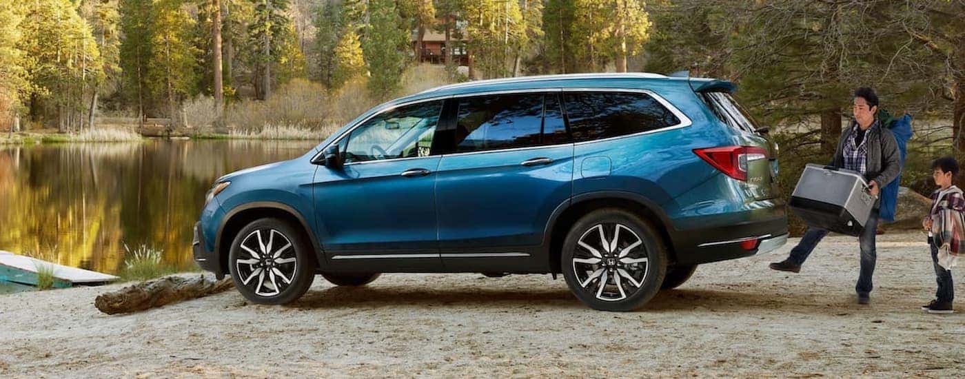A blue 2021 Honda Pilot Elite is shown from the side parked near a remote picnic area.
