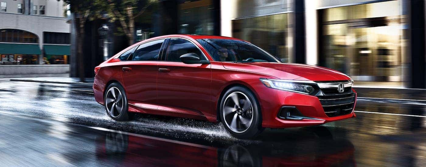 A red 2022 Honda Accord Sport is shown driving down a city street after leaving a used Honda dealership.