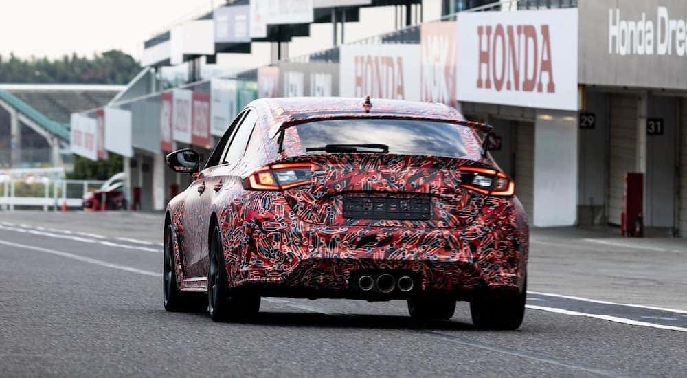 A multicolored 2023 Honda Civic Type R Prototype is shown from behind at a racetrack.