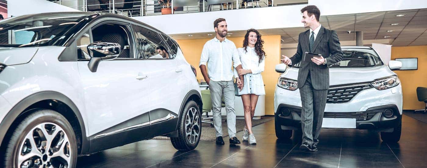People are shown in a car dealership while going through the 'sell my car' process.