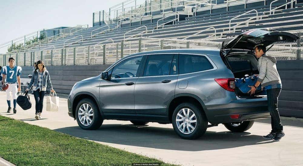 A grey 2022 Honda Pilot is shown from the rear while being unloaded in front of bleachers.