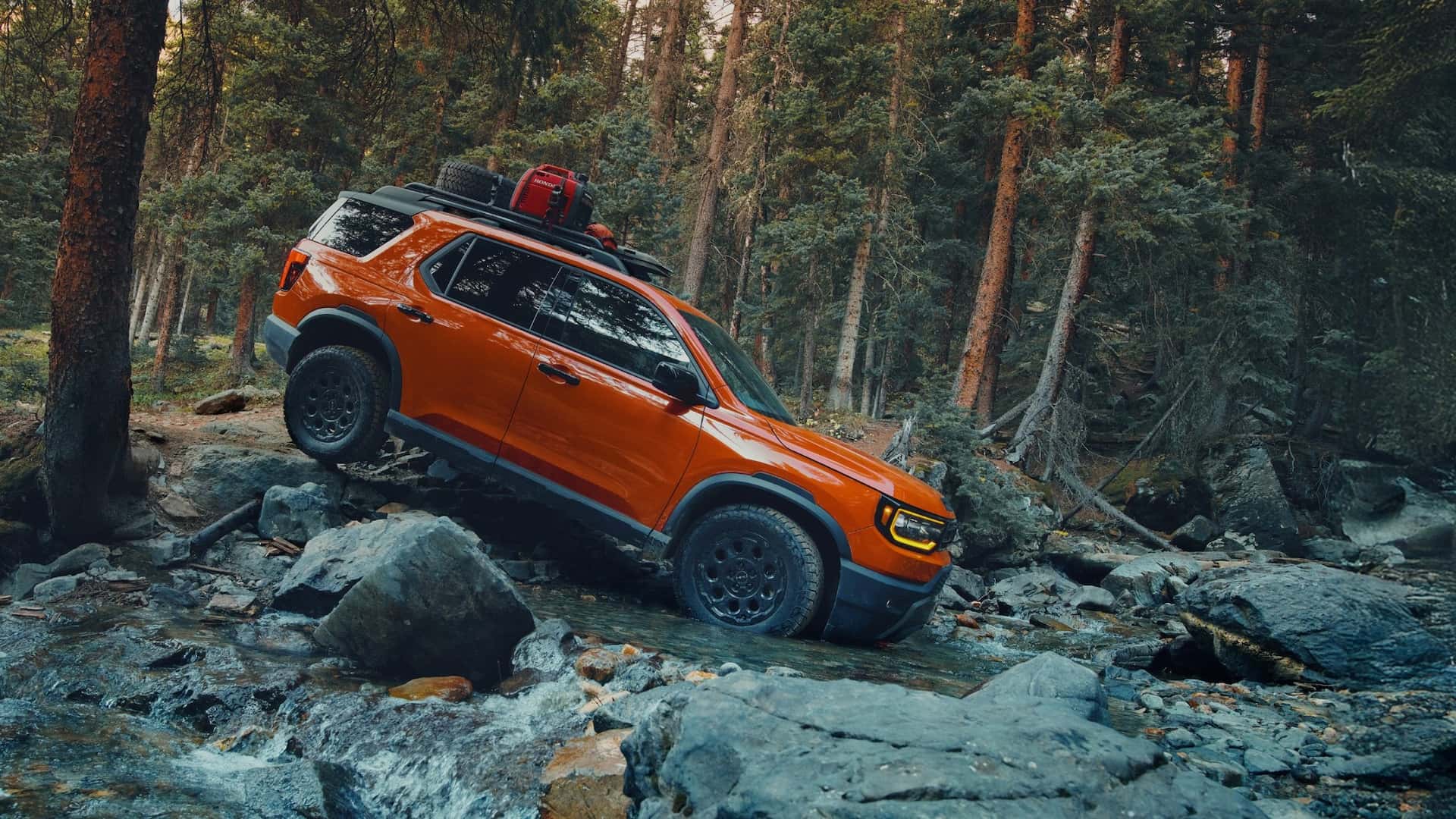 An orange Honda Passport driving over a creek