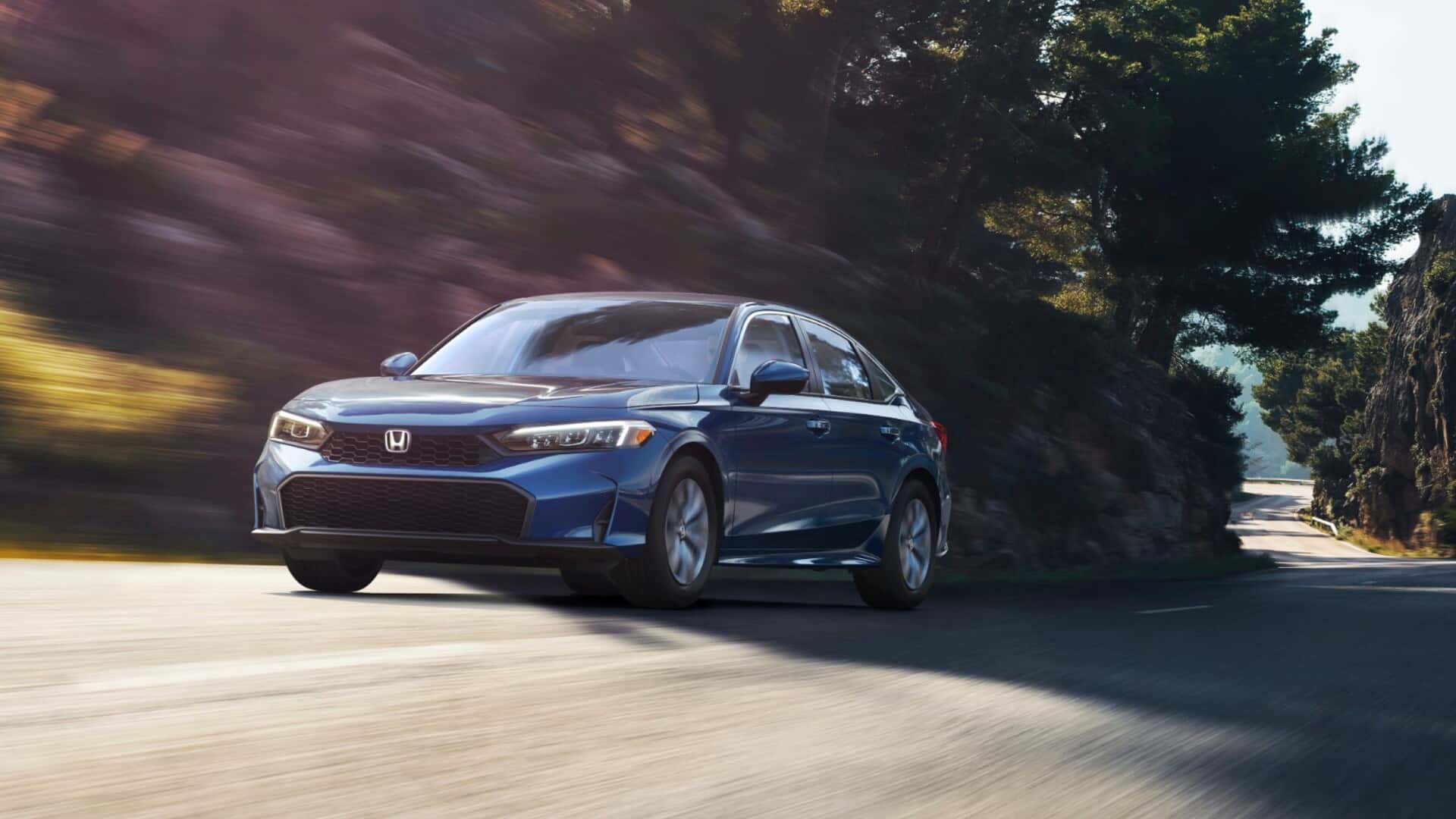 A blue Honda Civic driving quickly down a road in a shallow ravine