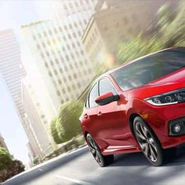 Front angled view of a red Honda Civic Sport driving through the city