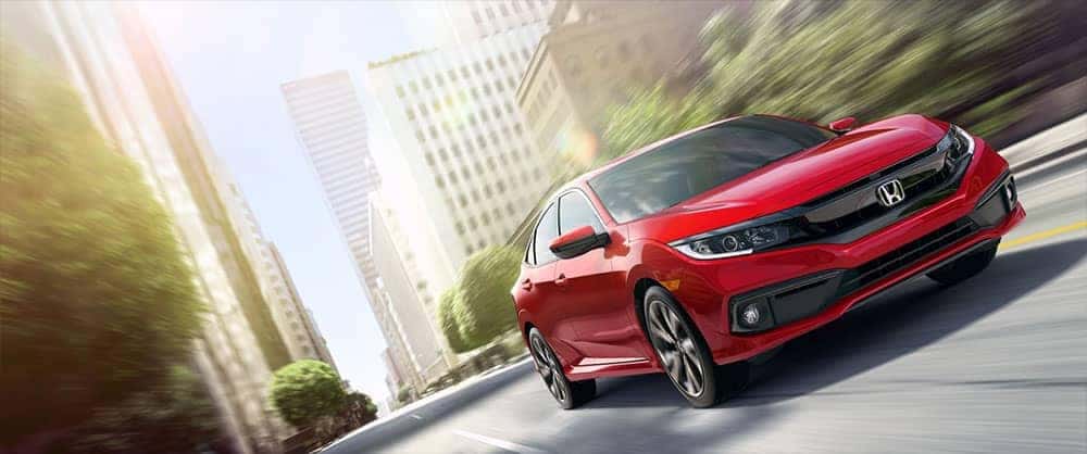 Front angled view of a red Honda Civic Sport driving through the city