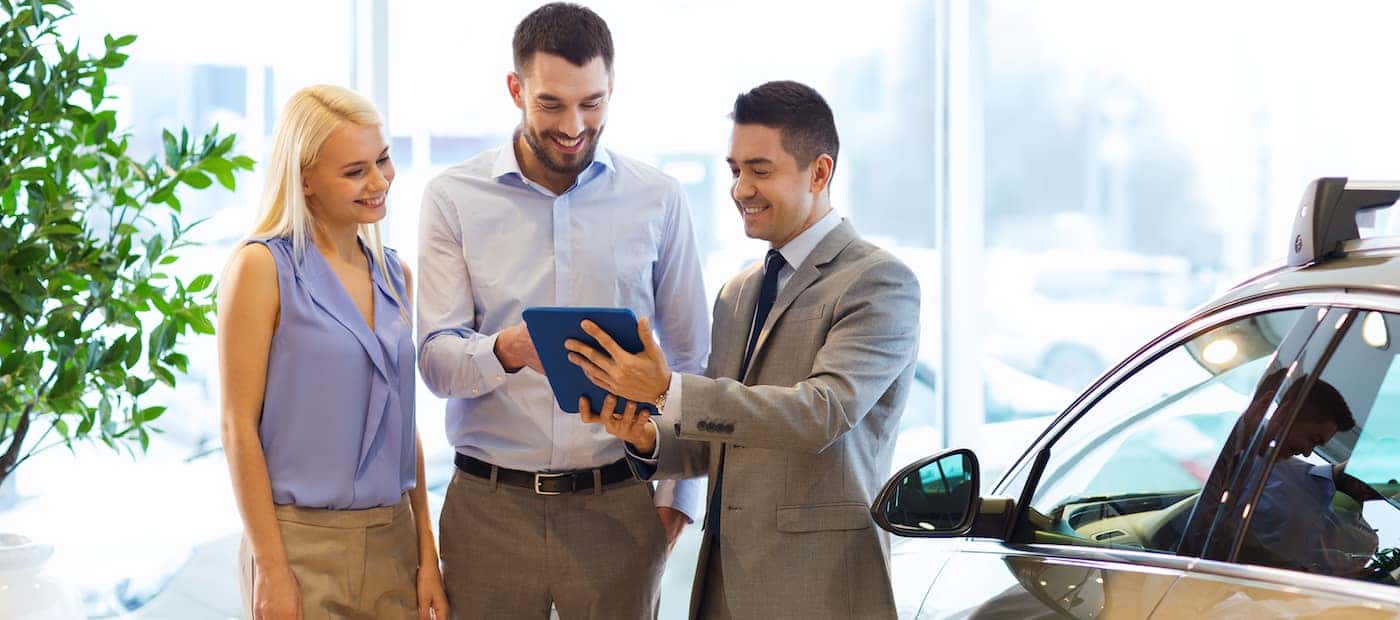 Smiling couple with an auto professional working to sell their car at a Honda dealership in Williston