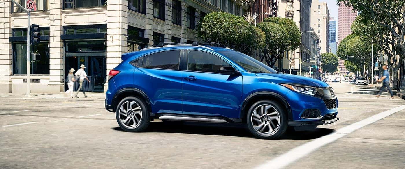 Side view of a blue Honda HR-V driving through a city
