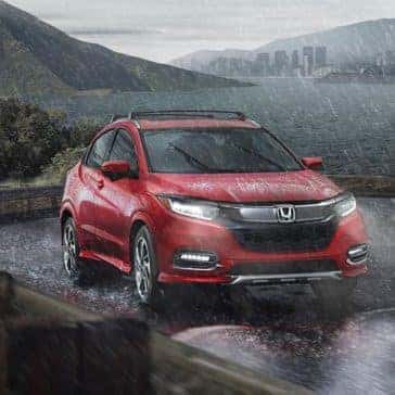 Front view of a red Honda HR-V driving through the pouring rain