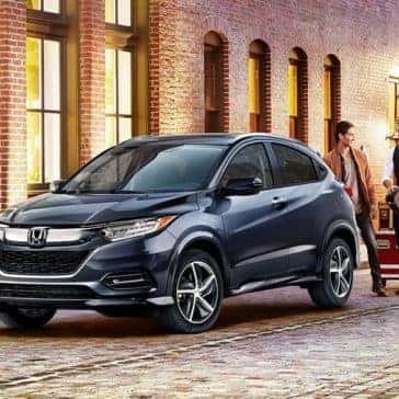 Musicians walking toward a dark colored Honda HR-V parked in the city