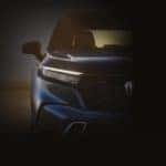 A closeup shows the passenger side headlight on a blue 2023 Honda CR-V surrounded in darkness.
