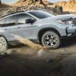A grey 2022 Honda Passport Trailsport is shown from the front at an angle while driving off-road.