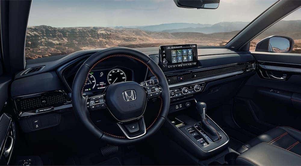 The black interior of a 2023 Honda CR-V is shown from the driver's seat.