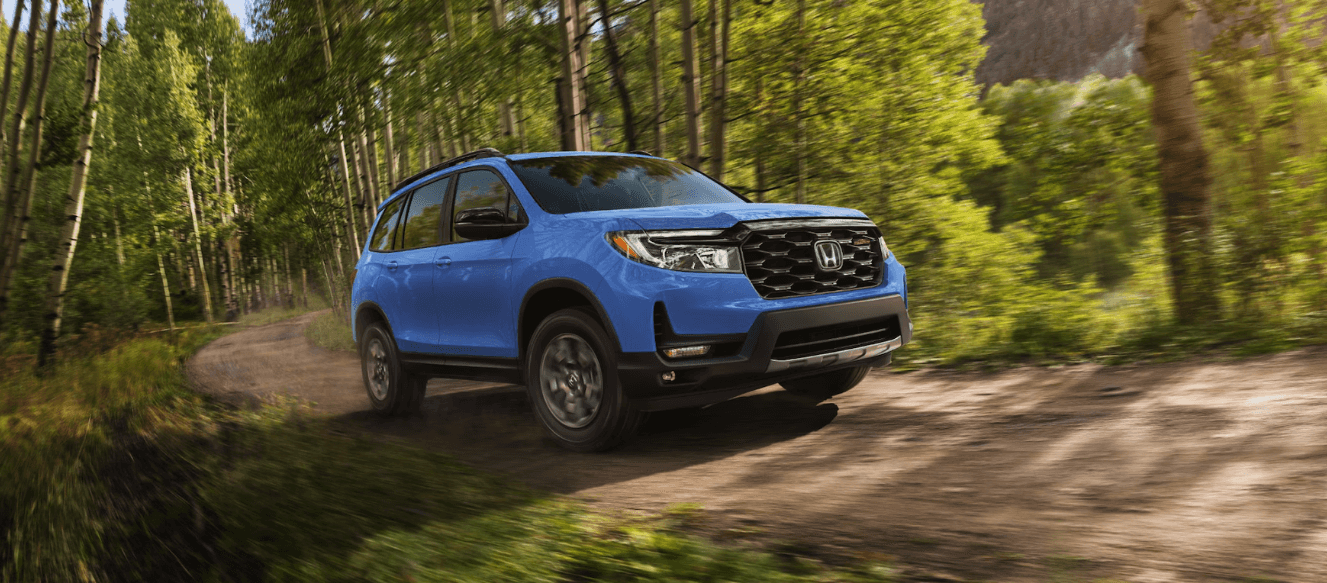 2025 Honda Passport TrailSport in Diffused Sky Blue Pearl on a dirt road surrounded by trees