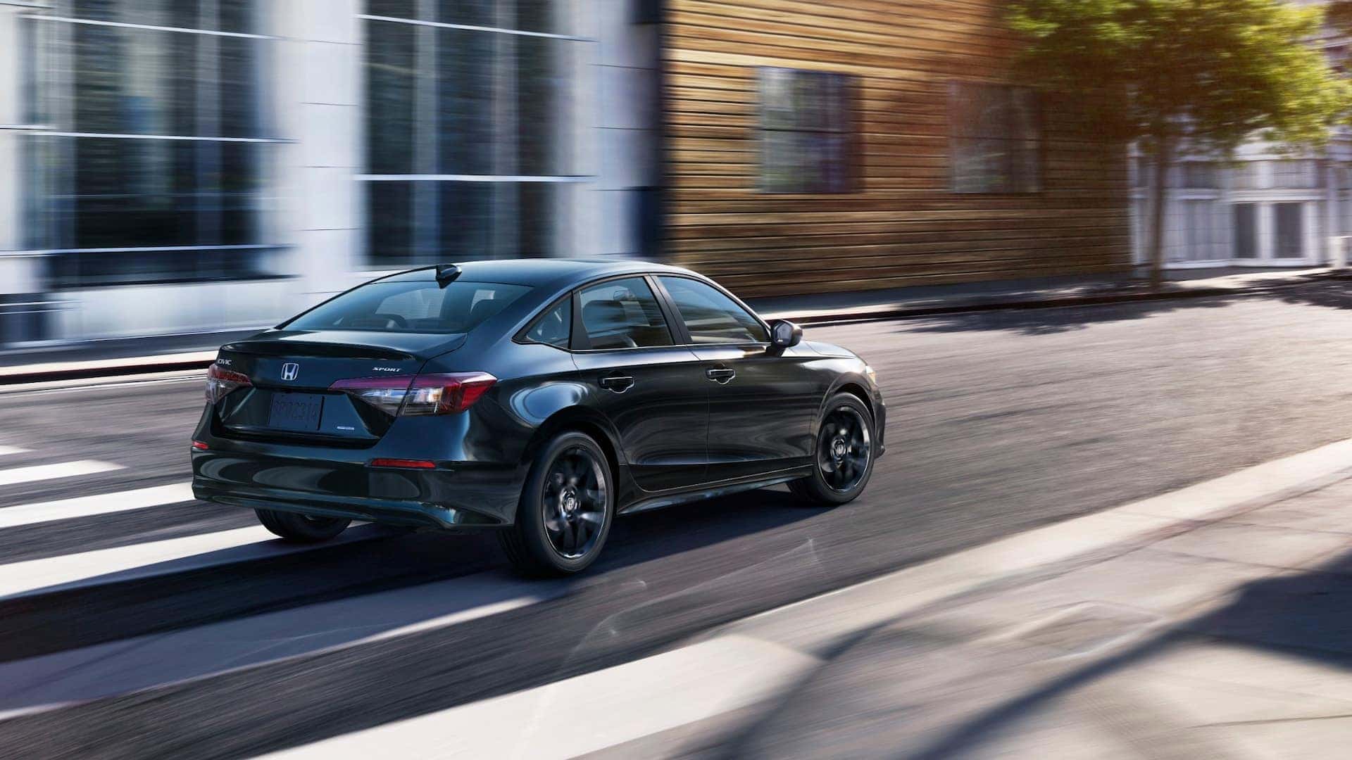 A black Honda Civic Hybrid driving quickly through the city