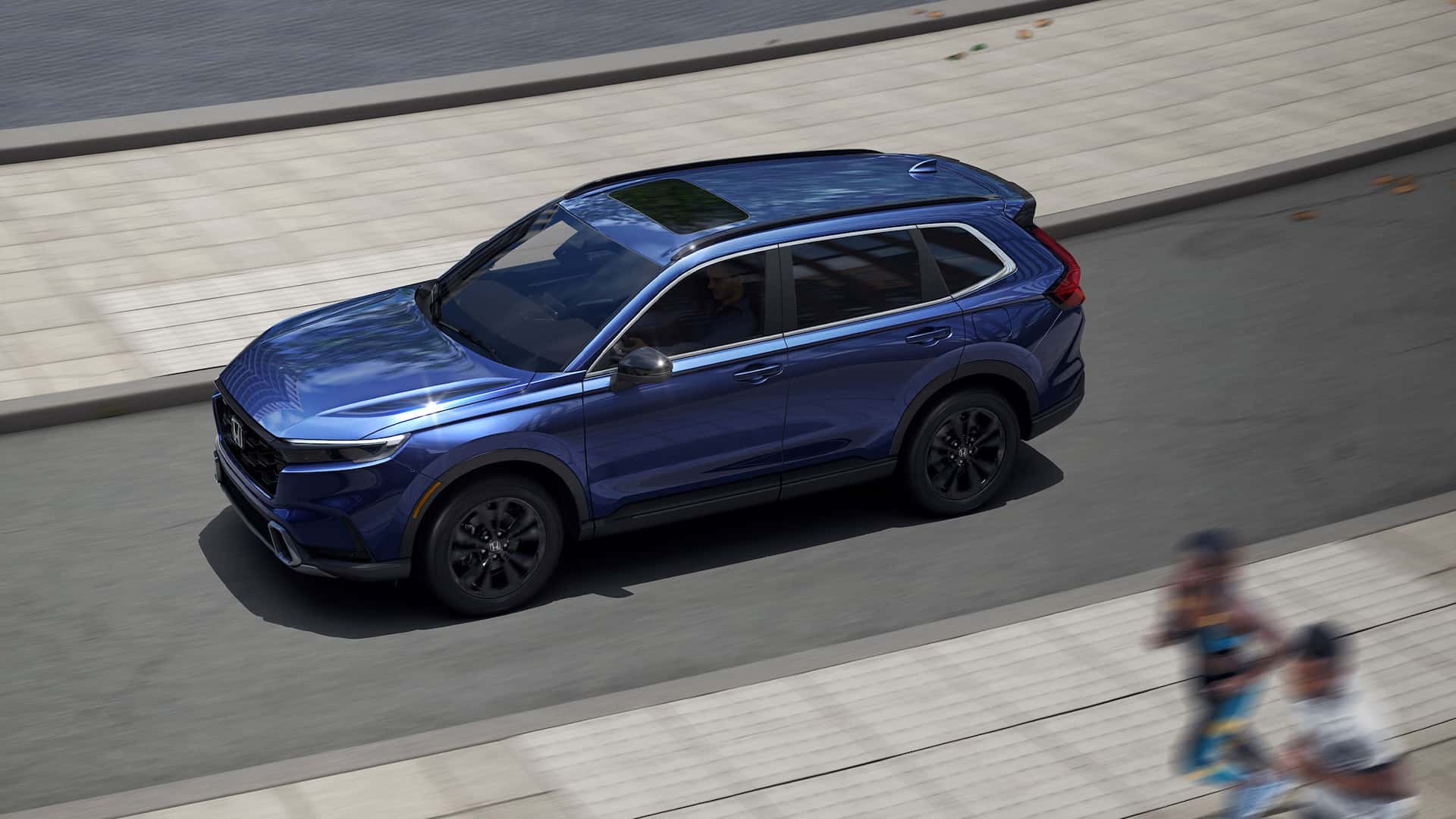 A blue Honda CR-V driving quickly down the road by a pair of joggers