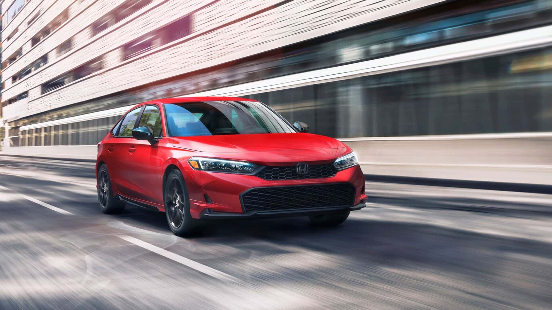 A red Honda Civic driving quickly through a city
