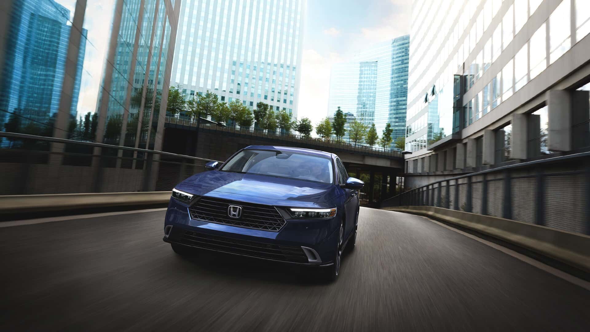A blue Honda Accord driving through a city