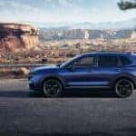 A blue Honda CR-V in profile, parked near a rocky plateau in a desert.