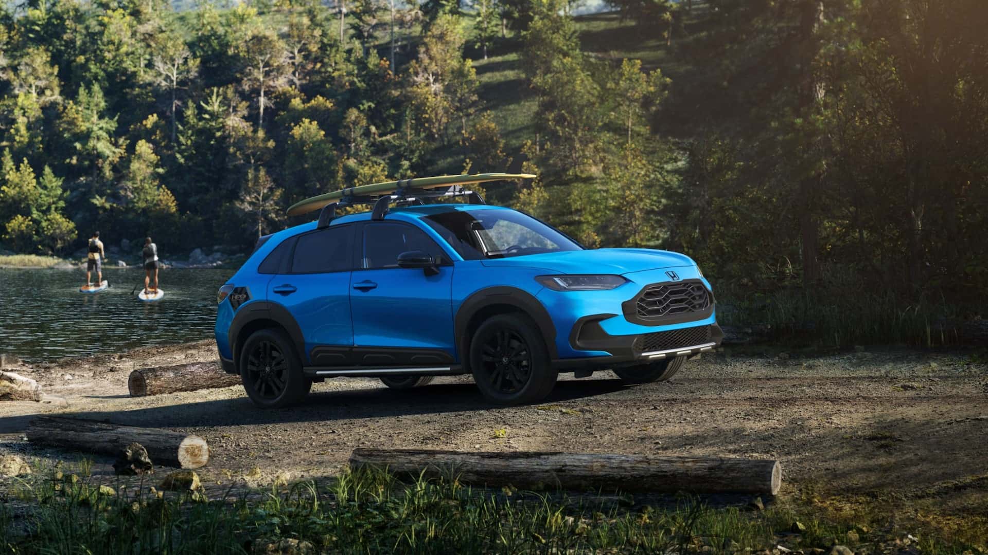 A blue Honda HR-V parked by a lake in a forest on a dirt road
