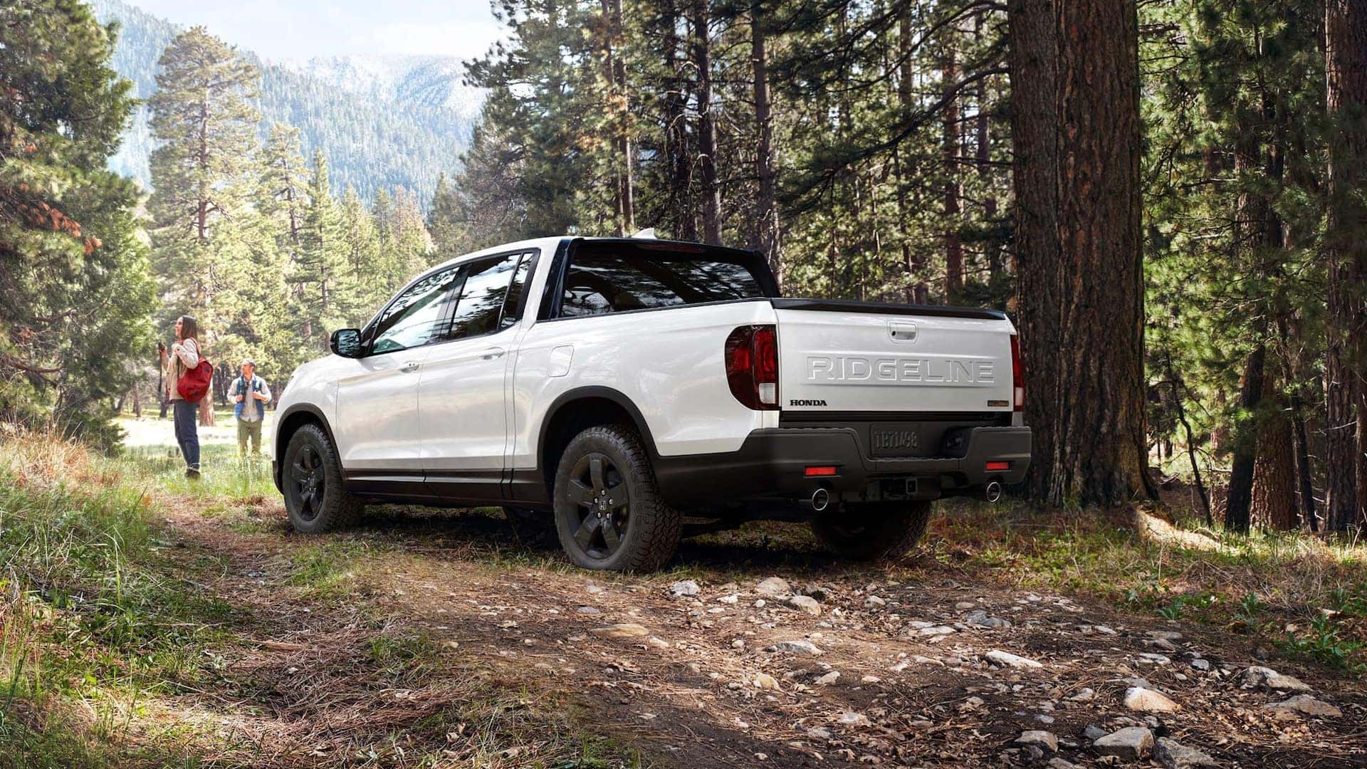 A white Honda Ridgeline parked on a forest trail