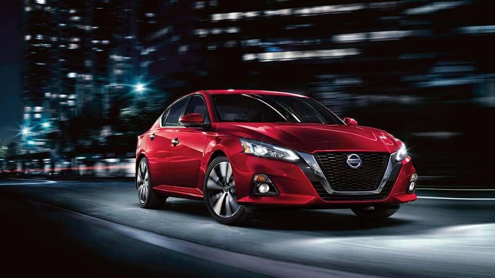 Front view of a red 2020 Nissan Altima driving through the city at night