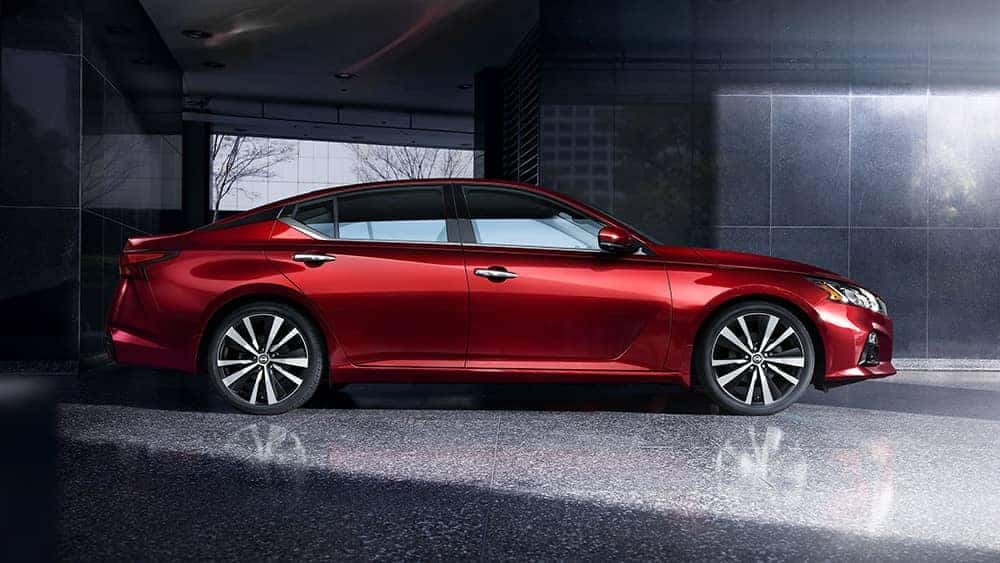 Side view of a red 2020 Nissan Altima parked by a modern building