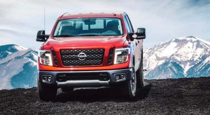 A red 2018 Nissan Titan is shown driving with distant snow covered mountains.