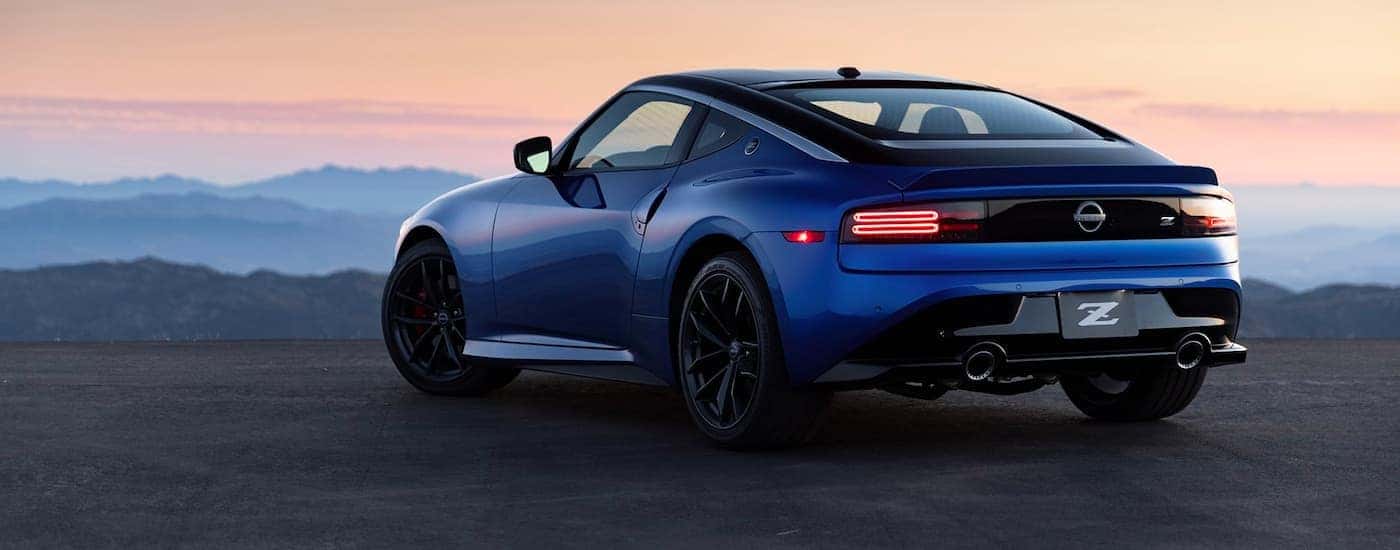 A blue 2023 Nissan Z is shown from behind with distant mountains.