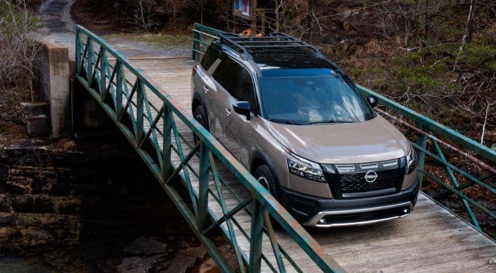 A brown 2023 Nissan Pathfinder Rock Creek is shown from the front while driving over a bridge.