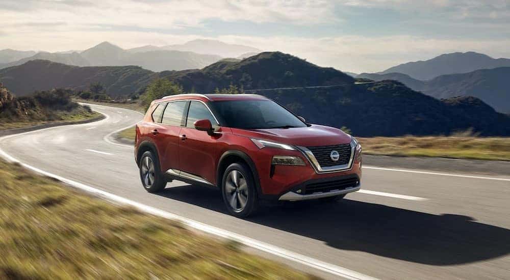 A red 2023 Nissan Rogue is shown driving on a highway after visiting a Nissan dealer serving Bismark.