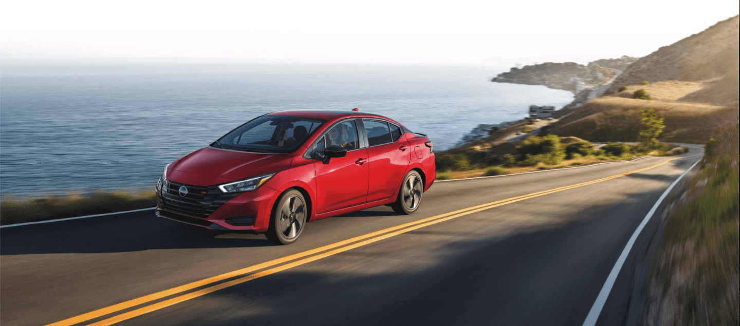 2024 Nissan Versa driving on the coast, past a body of water