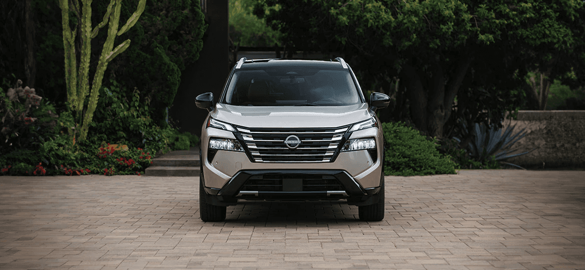Front view of the 2024 Nissan Rogue in front of a garden