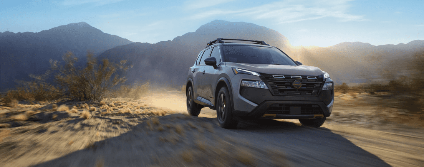 2025 Nissan Rogue Rock Creek on a dirt road with mountains in the background