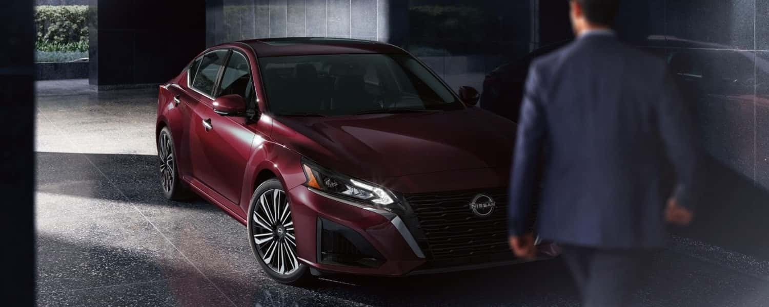 A man walking in front of a parked, red 2025 Nissan Altima