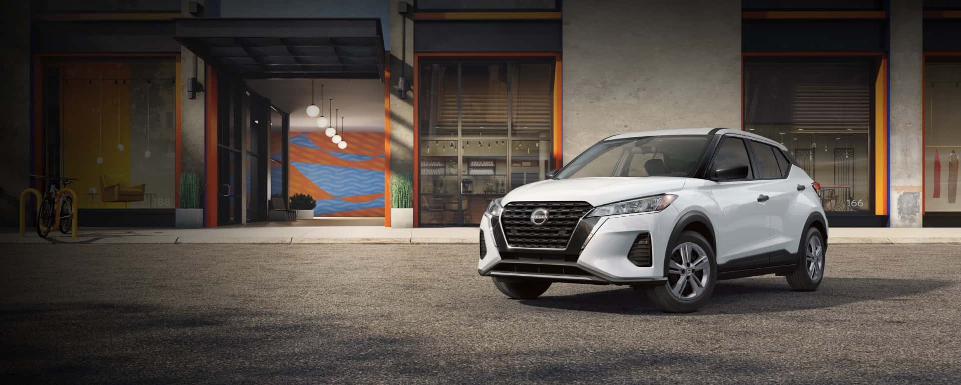 A white 2025 Nissan Kicks parked outside of a building.