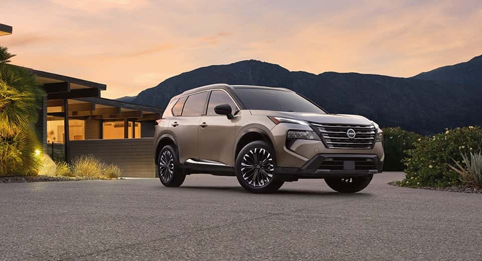 A light brown Nissan Rogue parked outside of a nice house in a desert region