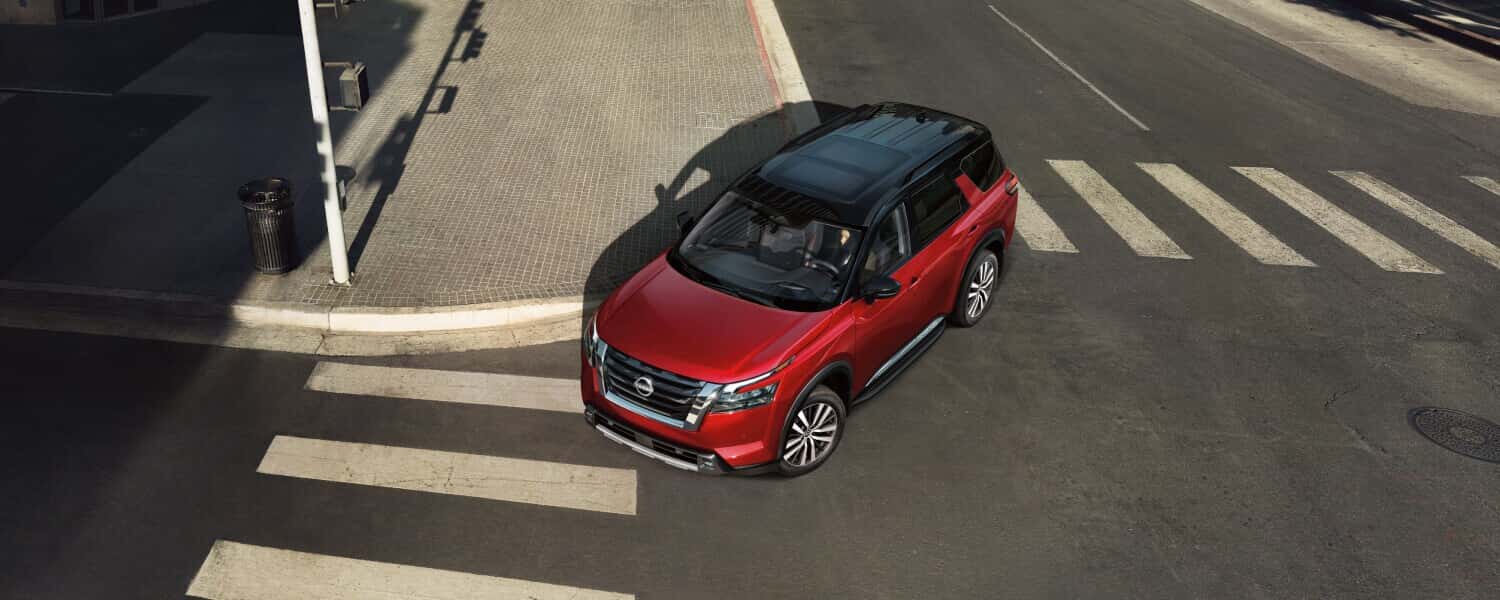 A red Nissan Pathfinder turning a corner in a town