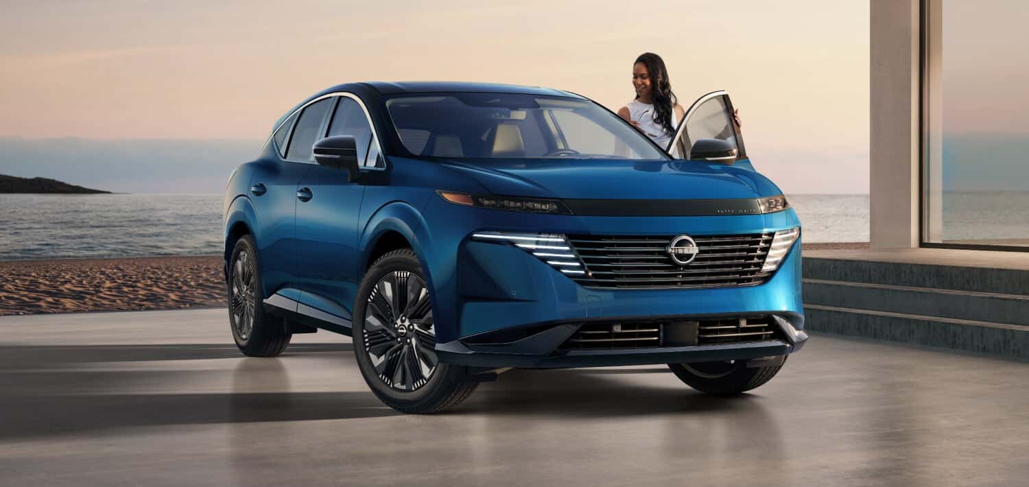 A woman getting into a blue Nissan Murano near a beach