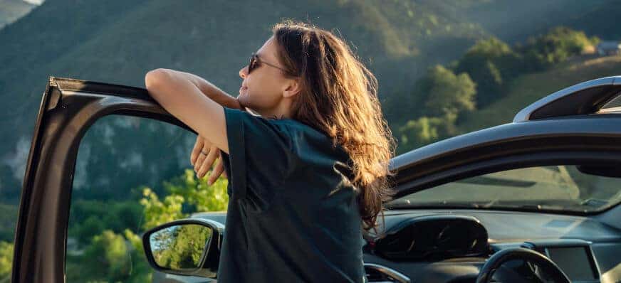 Lady standing within her car door.