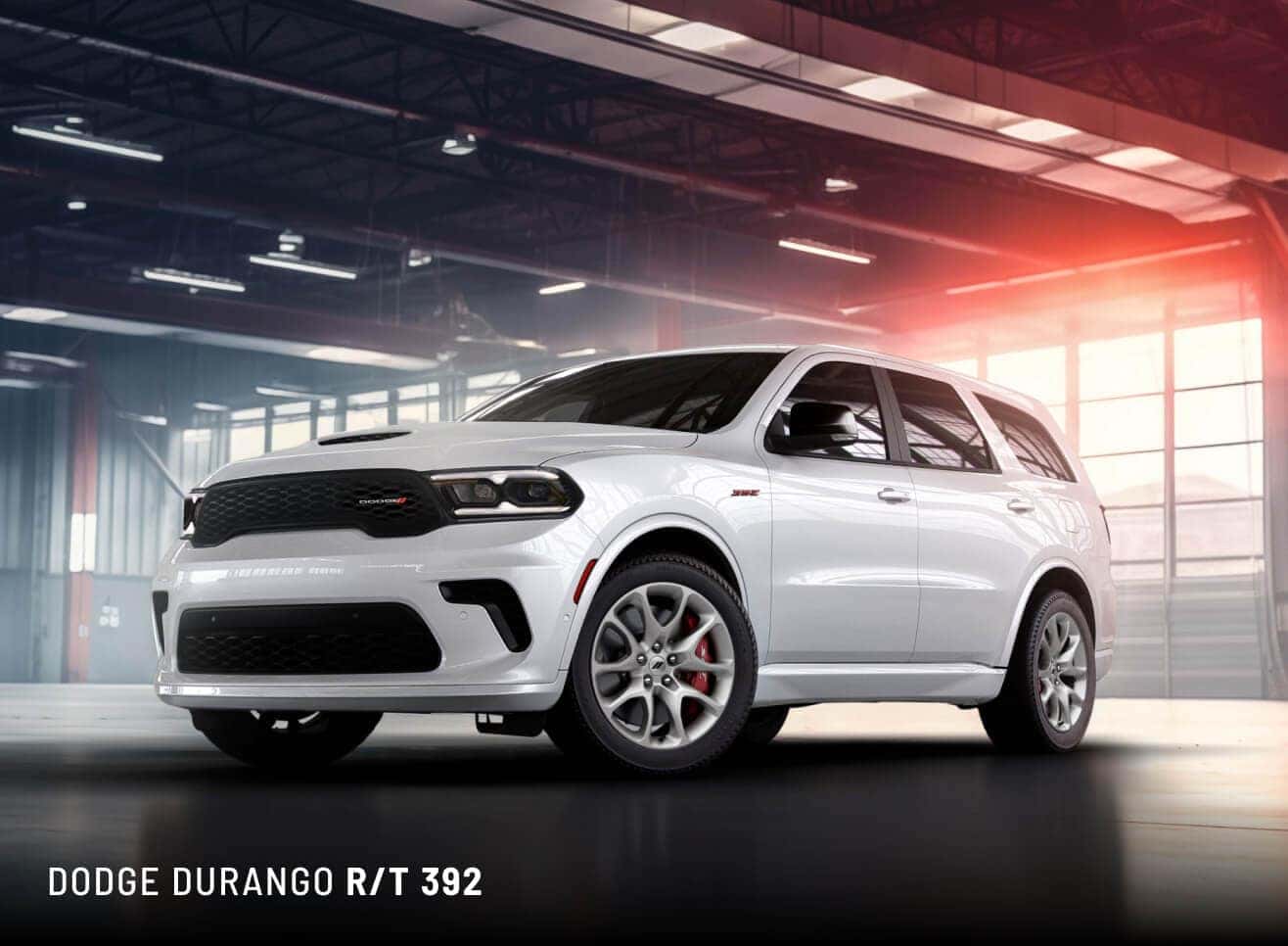 Low-angle front three-quarter view of a white 2027 Dodge Durango R/T 392 in a garage with glowing windows.